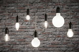Verschiedene Filament-Glühbirnen mit schwarzer Fassung vor grauer Backsteinwand, Beleuchtung und Lampen.