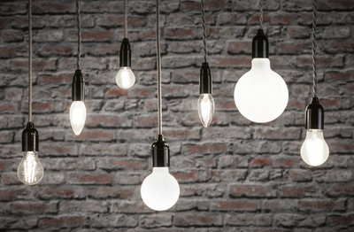 Verschiedene Filament-Glühbirnen mit schwarzer Fassung vor grauer Backsteinwand, Beleuchtung und Lampen.