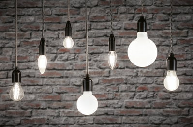 Verschiedene Filament-Glühbirnen mit schwarzer Fassung vor grauer Backsteinwand, Beleuchtung und Lampen.