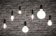 Différents ampoules filament avec douilles noires suspendues devant un mur en briques grises, éclairage.