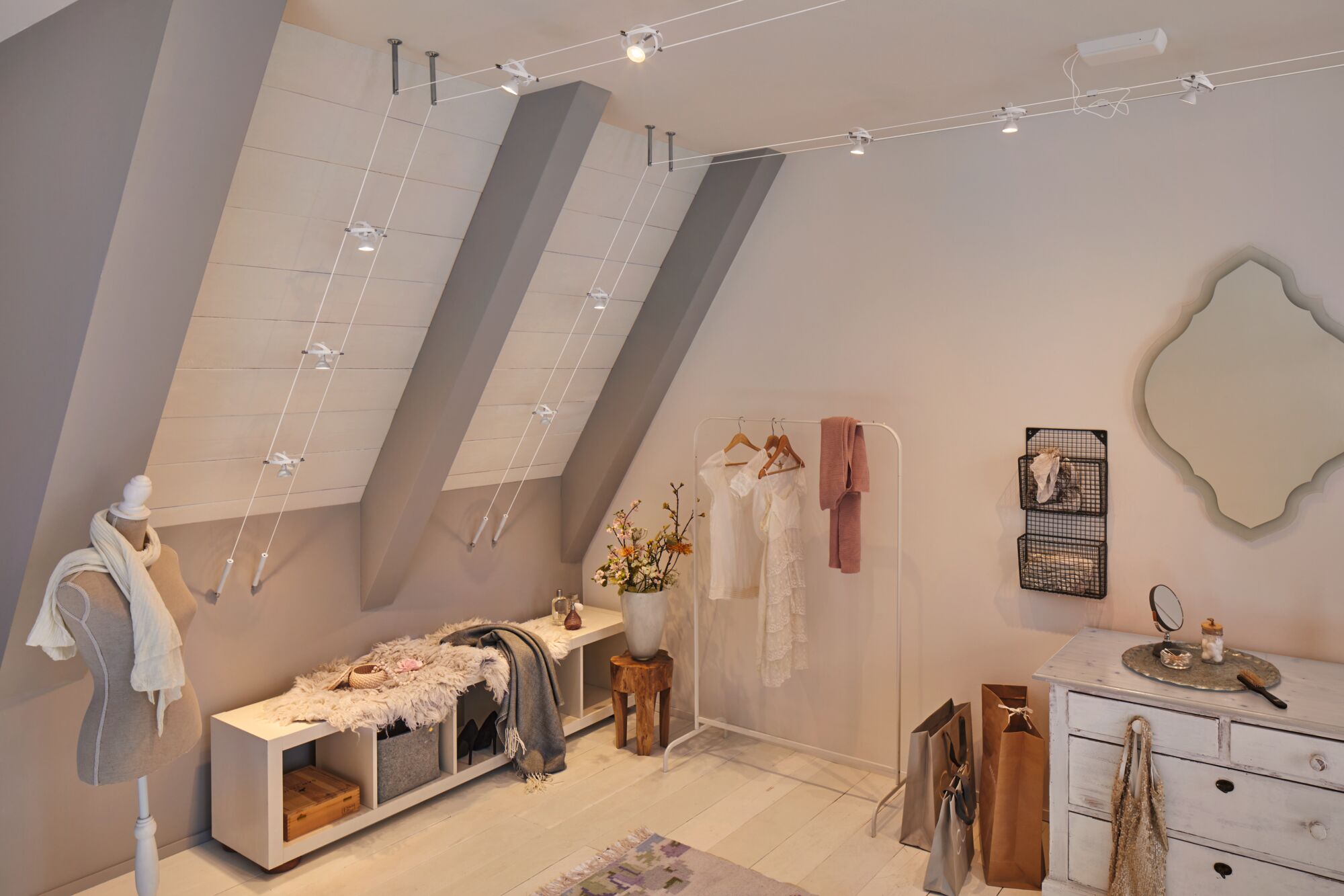 Modernes Zimmer mit weißem Seilspannsystem und LED-Strahlern an schräger Decke für flexible Beleuchtung