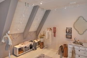 Modernes Zimmer mit weißem Seilspannsystem und LED-Strahlern an schräger Decke für flexible Beleuchtung