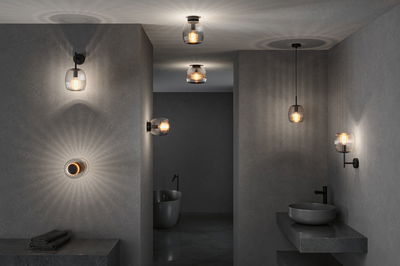 Modern bathroom lighting with black metal fixtures and ribbed glass shades creating ambient light effects.