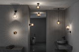 Modern bathroom lighting with black metal fixtures and ribbed glass shades creating ambient light effects.