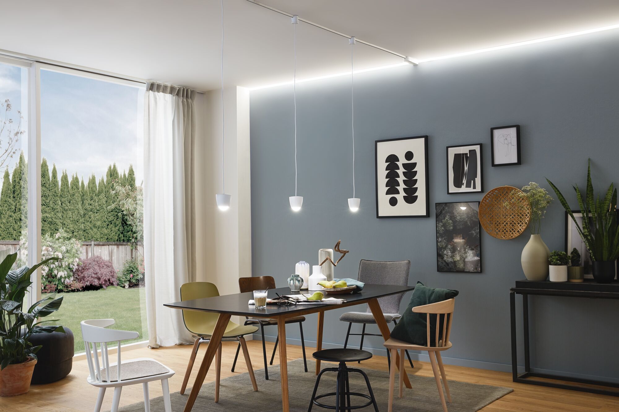Modernes Esszimmer mit schwarzem Tisch, gemischten Stühlen und weißer LED-Schienenbeleuchtung an der Decke