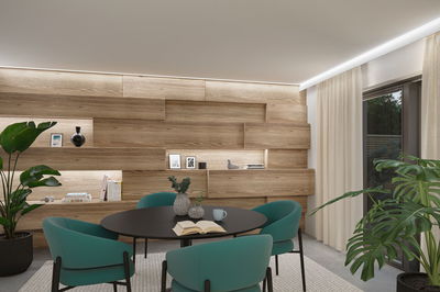 Modernes Esszimmer mit schwarzem Tisch, türkisfarbenen Stühlen und Holzpaneelwand mit LED-Beleuchtung
