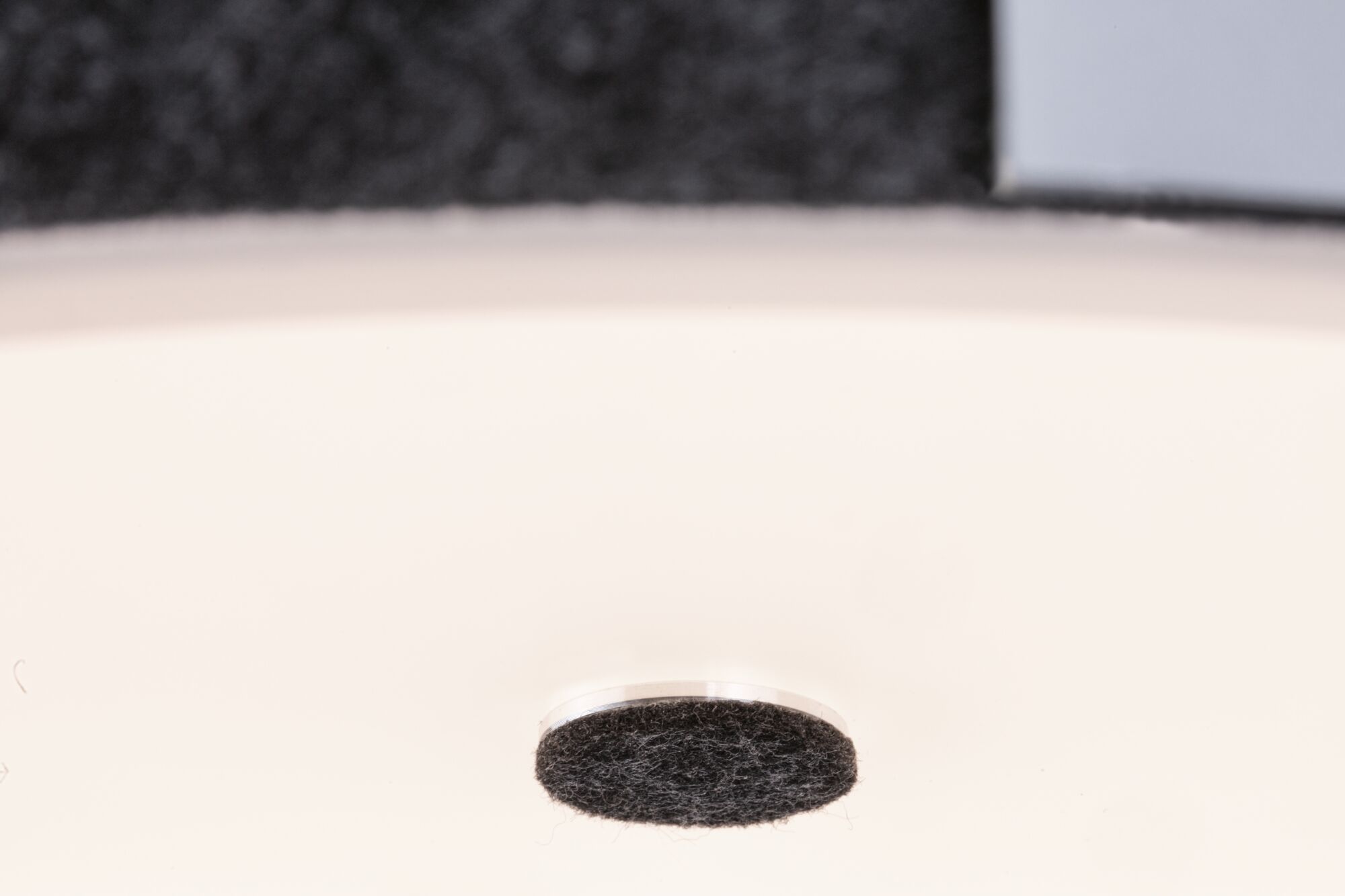 Patin en feutre noir sur surface blanche pour protéger les sols des rayures et réduire le bruit.