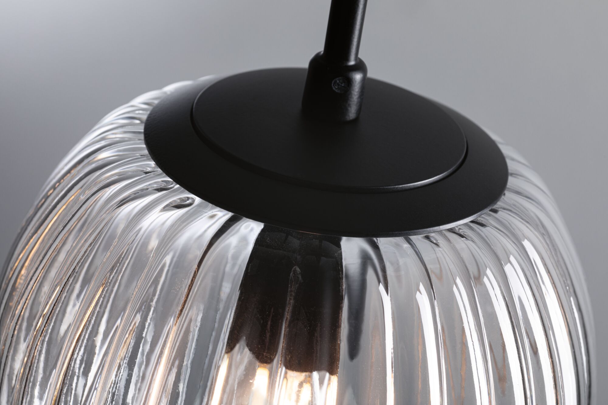 Close-up of clear ribbed glass pendant light with black metal holder for modern interior lighting