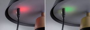 Nahaufnahme eines schwarzen Kabelanschlusses an einer grauen Lampenhalterung mit rotem und grünem Licht