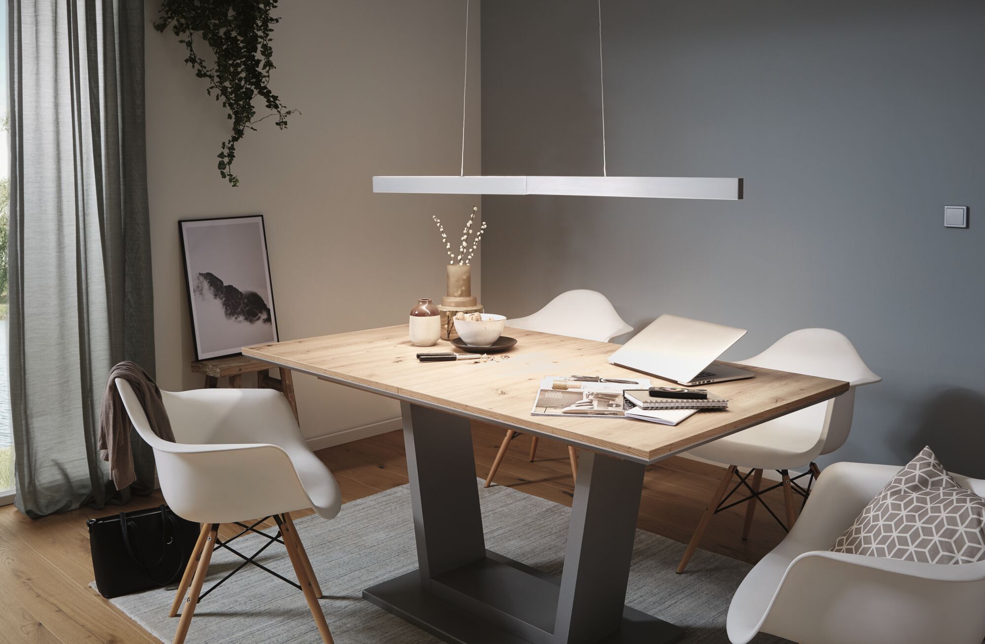 Modern dining area with wooden table and white plastic chairs under minimalist LED pendant light