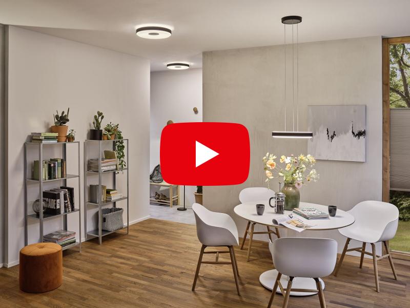 Salle à manger moderne avec table blanche, chaises et suspension minimaliste en bois et tons gris.