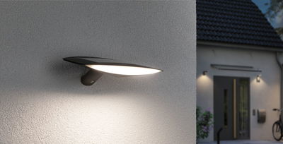 Moderne schwarze Außenwandleuchte mit breitem LED-Lichtschein an Hausfassade für Gartenbeleuchtung