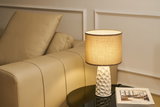 Beige lædersofa ved bord med hvid keramisk lampe og beige stofskærm til stuebelysning