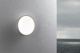 Round white outdoor wall light made of plastic on grey wall with sea background, LED lighting