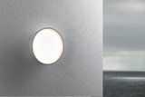 Runde weiße Außenwandleuchte aus Kunststoff an grauer Wand mit Meereshintergrund, LED Licht