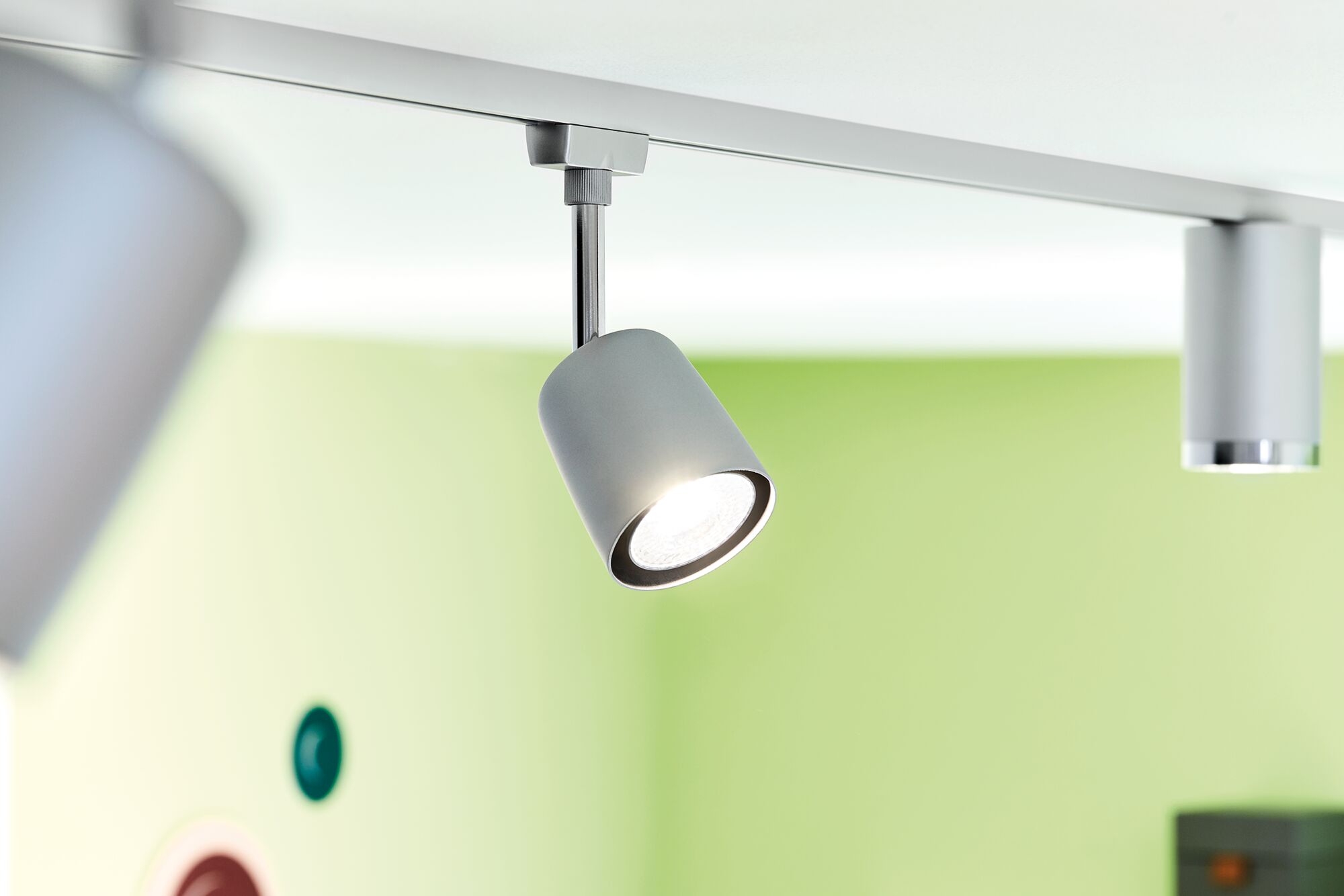 Spot LED gris moderne sur rail de plafond avec fond vert pour éclairage intérieur