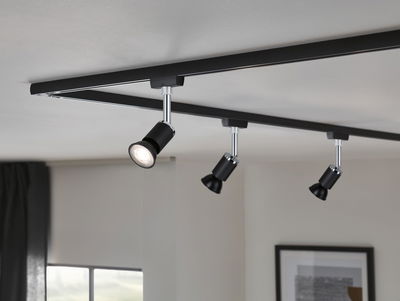 Black metal LED track light with three adjustable spotlights mounted on white ceiling