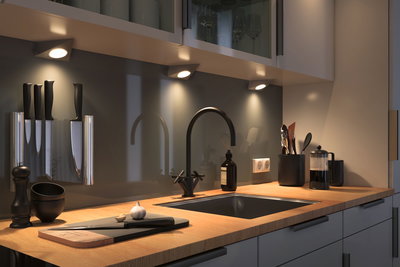 Plan de travail de cuisine moderne en bois avec évier noir, robinet et éclairage LED sous meuble pour cuisine.