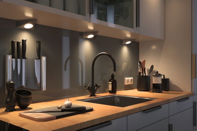 Modern kitchen countertop with wood surface, black sink, faucet, and LED under-cabinet lights for kitchen lighting.