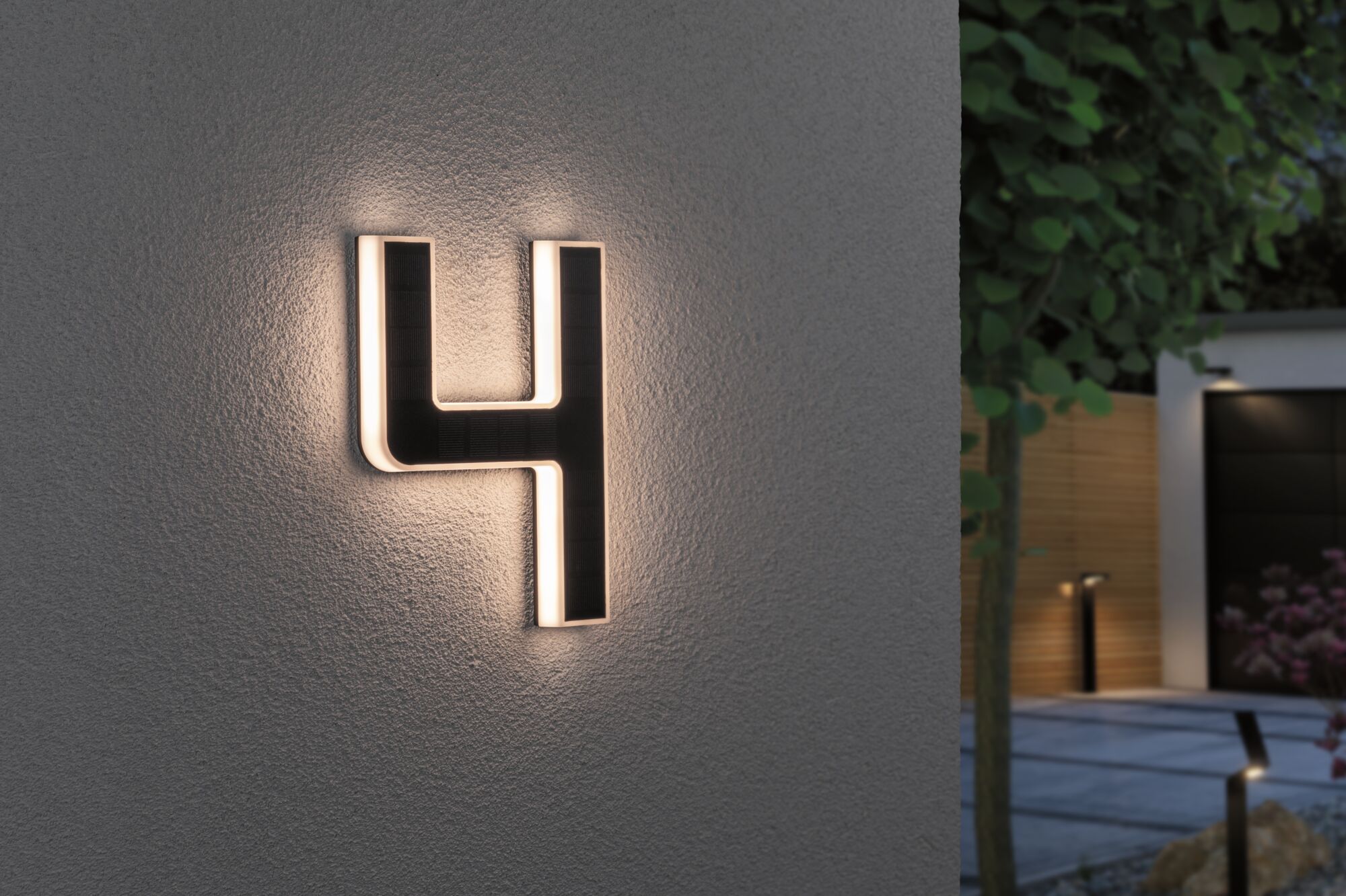 Illuminated house number 4 in black with warm white LED light mounted on gray exterior wall