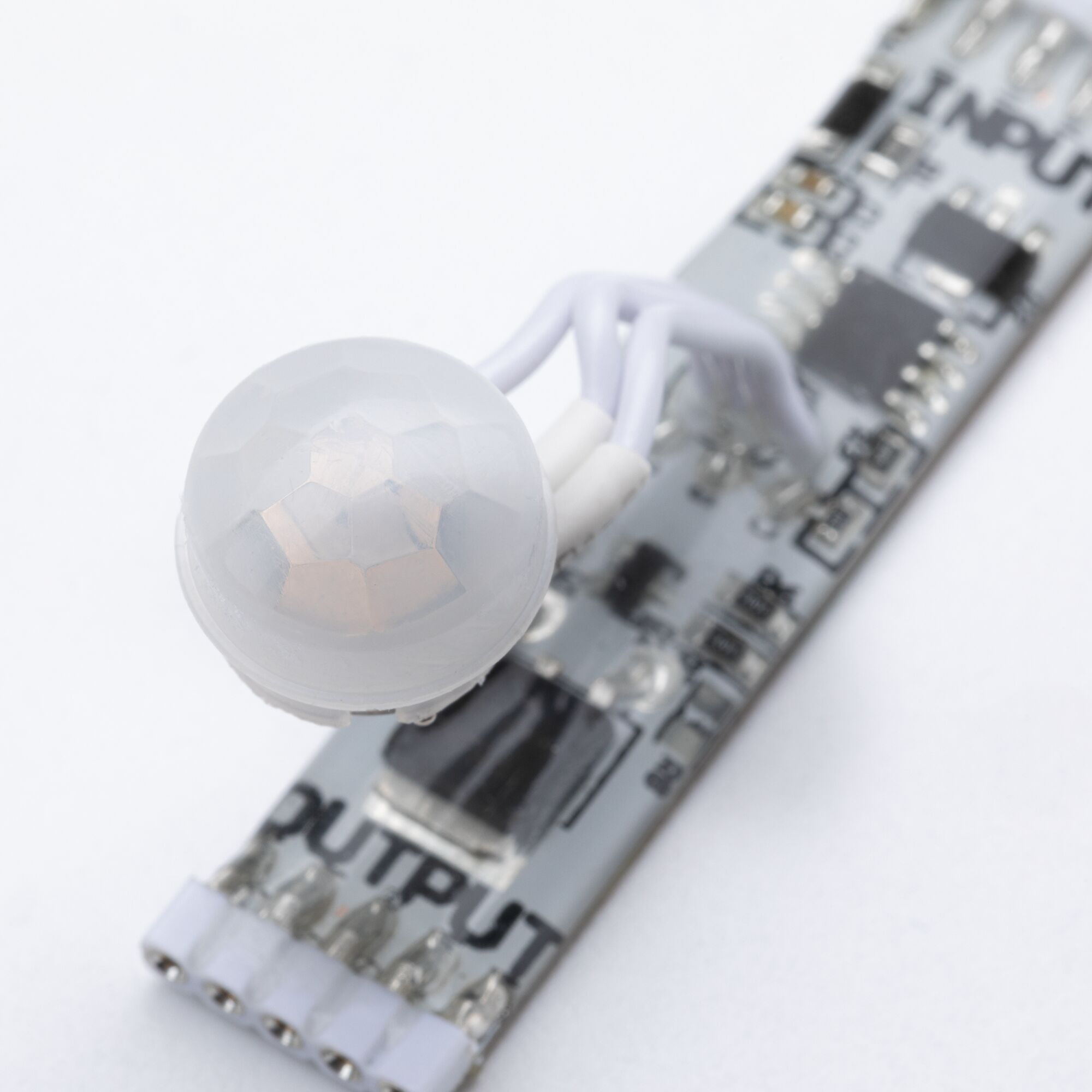 Gros plan d'un détecteur de mouvement PIR blanc avec lentille sur circuit imprimé pour éclairage LED
