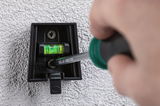 Black plastic wall mount with spirit level being fixed with screwdriver on textured wall surface