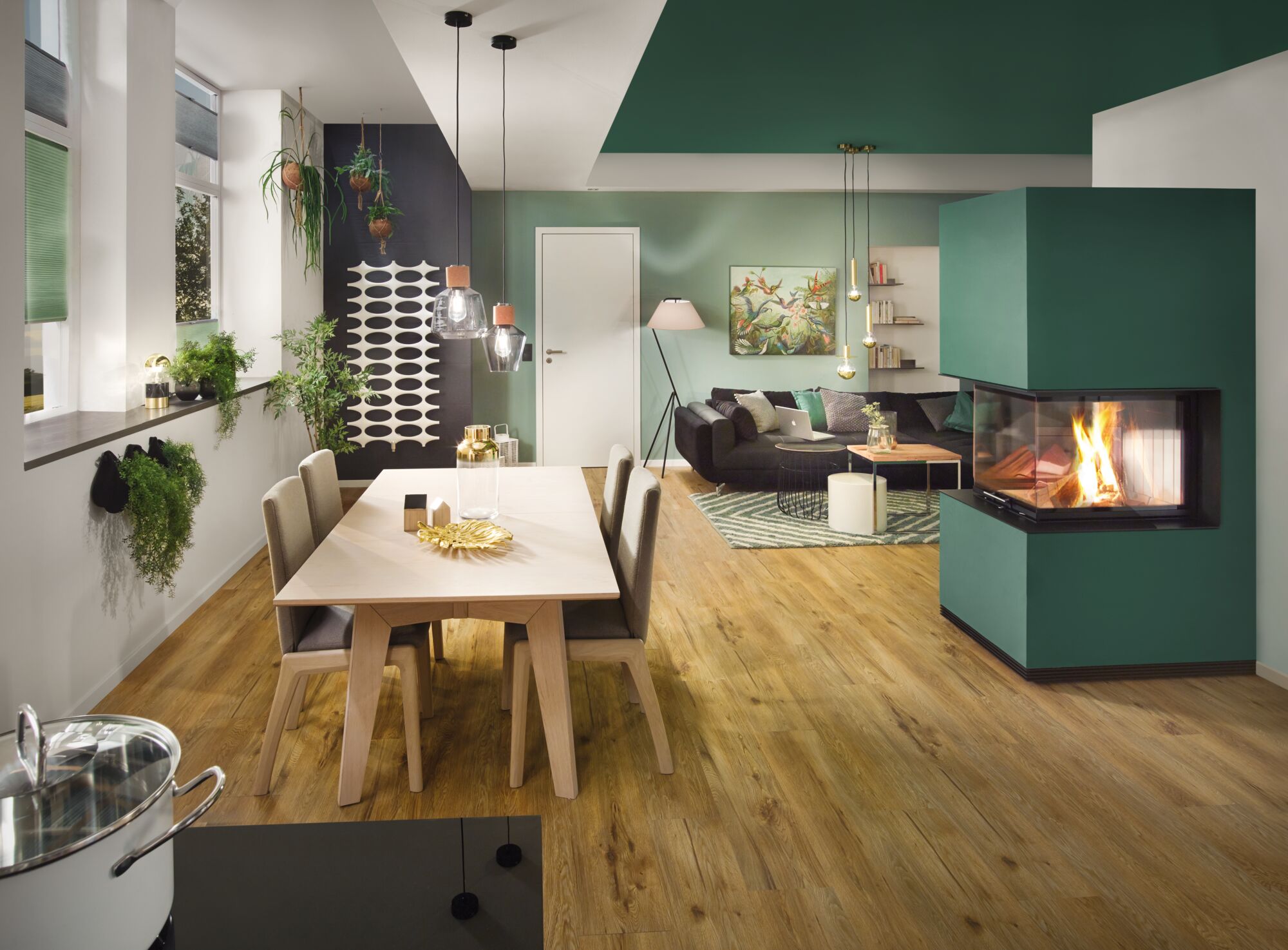 Moderne woonkamer met groene open haard, houten vloer, eettafel en hangplanten in urban jungle stijl