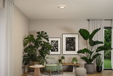Rundes Deckenlicht mit warmweißem LED-Licht in modernem Wohnzimmer mit grünen Pflanzen und beigem Sessel.