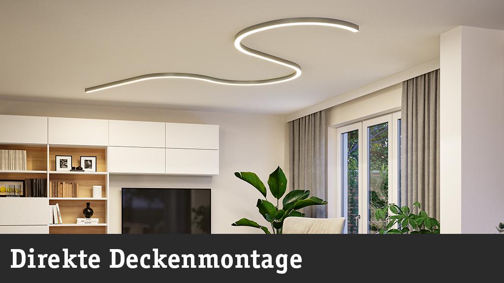 Moderne weiße LED-Deckenleuchte in geschwungener Form in hellem Wohnzimmer mit Pflanzen und TV.