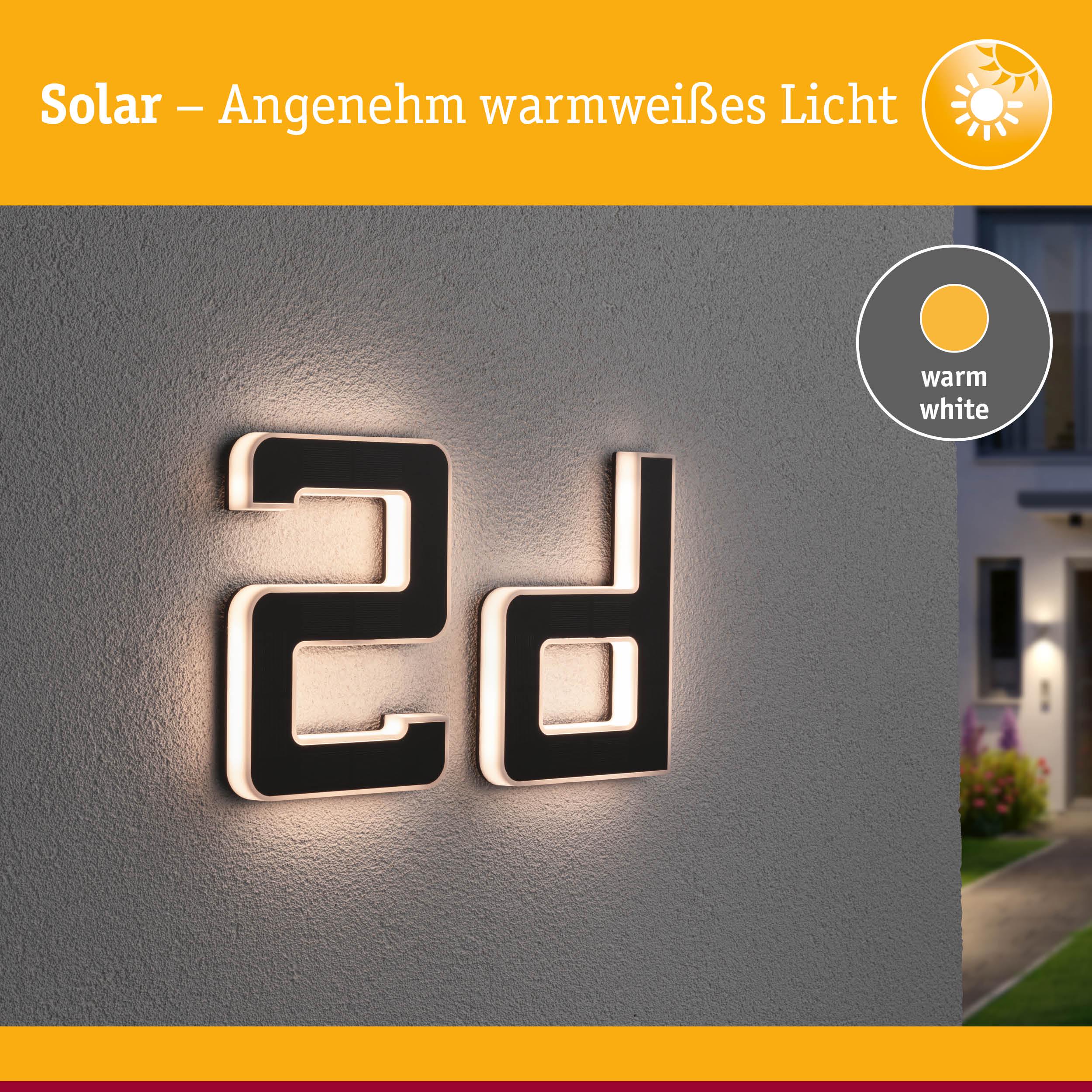 Solarhausnummer 2d aus schwarzem Material mit warmweißem Licht an grauer Wand beleuchtet