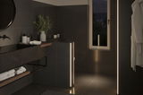 Modern bathroom with black tiles and warm white LED light strips creating ambient lighting effect