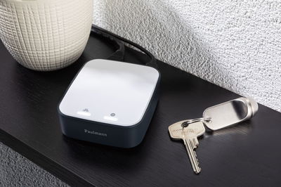 Kompaktes Paulmann Smart Home Gateway in Schwarz-Weiß auf schwarzem Tisch neben Schlüsselbund.