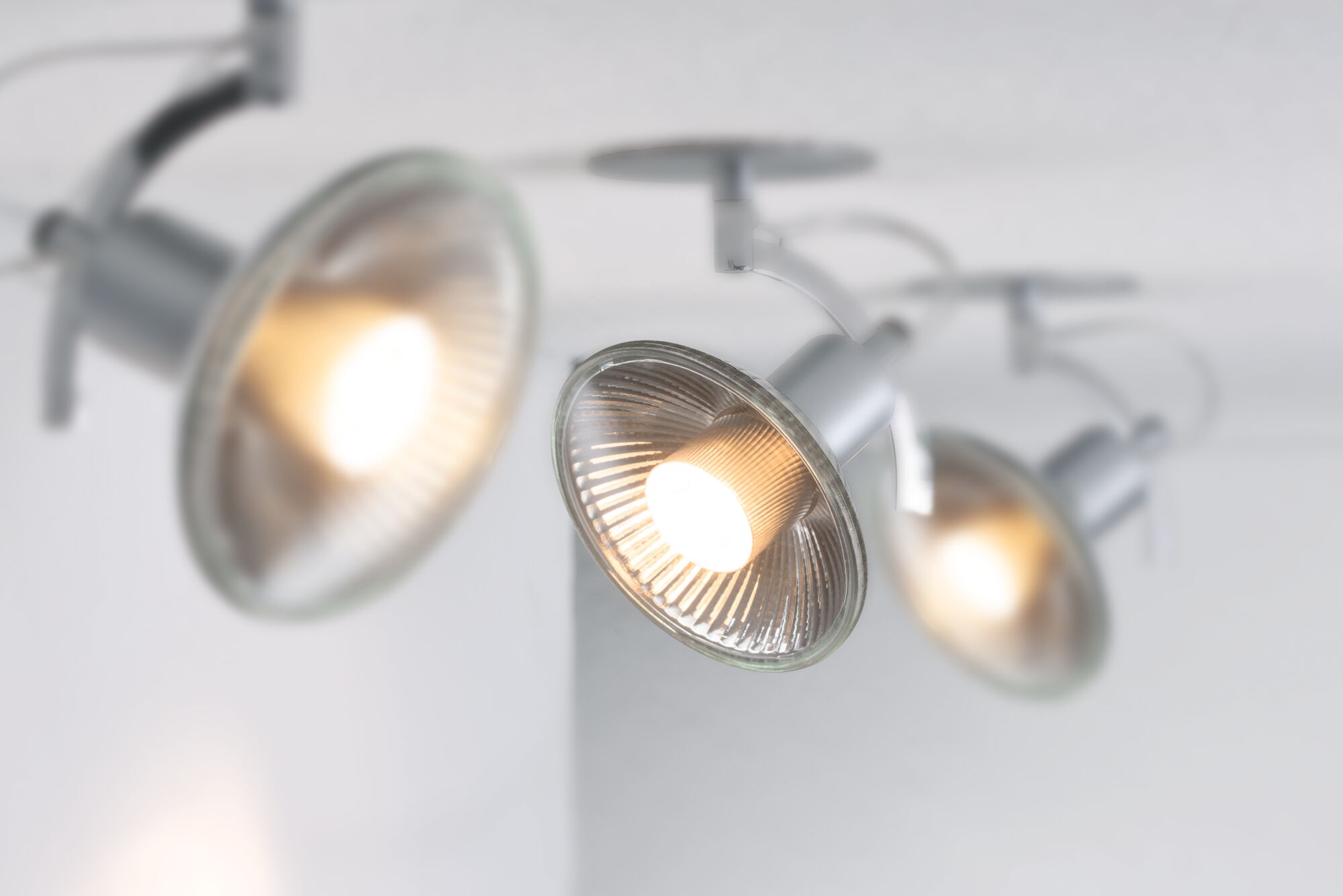 Drei silberne Deckenstrahler mit Glasreflektoren und warmweißem Licht für moderne Raumbeleuchtung