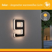 Solarbetriebene Hausnummer mit warmweißem Licht und schwarzem Rahmen an grauer Wand