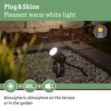 Black outdoor spotlight with warm white light on gravel for atmospheric garden and terrace lighting