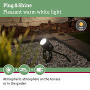 Black outdoor spotlight with warm white light on gravel for atmospheric garden lighting