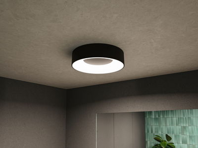Round black ceiling light with white diffuser in modern room featuring grey walls and green tile accent.