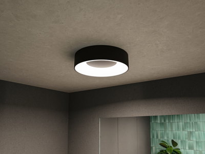 Round black ceiling light with white diffuser in modern room featuring grey walls and green tile accent.