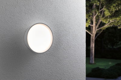 Applique murale extérieure LED ronde blanche sur mur gris avec lumière douce pour jardin