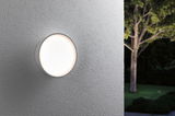 Round white LED outdoor wall light on grey wall emitting soft light for garden lighting