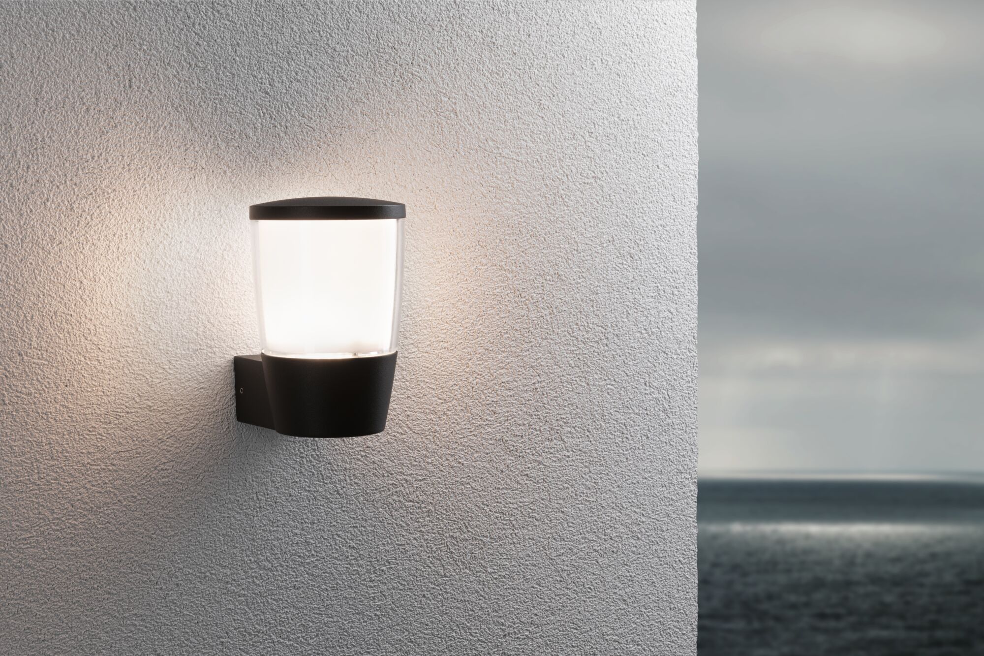 Schwarze Außenwandleuchte mit weißem Glas an weißer Wand, stimmungsvolle Beleuchtung für Terrasse