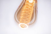 Close-up of warm white LED bulb with decorative filament and amber-colored glass for ambient lighting