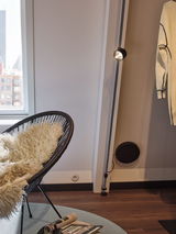 Modern black floor lamp with adjustable spotlight in cozy living room with chair and fur throw.