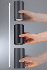 Three black cylindrical metal LED pendant lights held by hands, showing adjustable height feature.