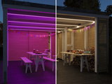 Comparison of warm white and violet LED ceiling lights in modern wooden shelter with table and benches
