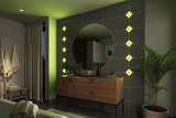 Modern bathroom with wooden vanity, round mirror, and green LED wall lights creating ambient lighting
