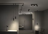 Modern black LED spotlights and pendant lights in minimalist room with grey walls and furniture