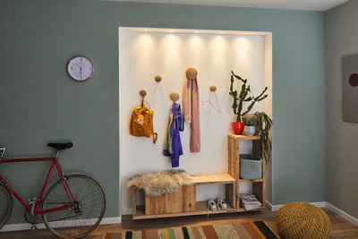 Bright wooden hallway shelf with bench, coat hooks, and LED spotlights, modern home lighting.