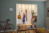 Helles Flurregal aus Holz mit Sitzbank, Garderobenhaken und LED-Spots, modernes Wohnraumlicht.