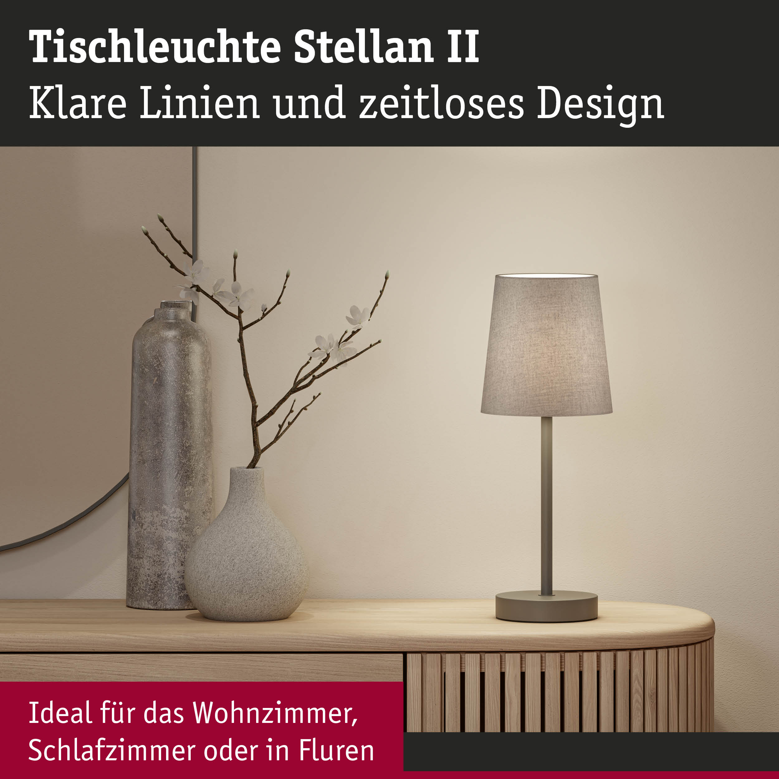 Tischleuchte Stellan II mit grauem Stoffschirm und Metallfuß auf Holzkommode neben Deko-Vasen